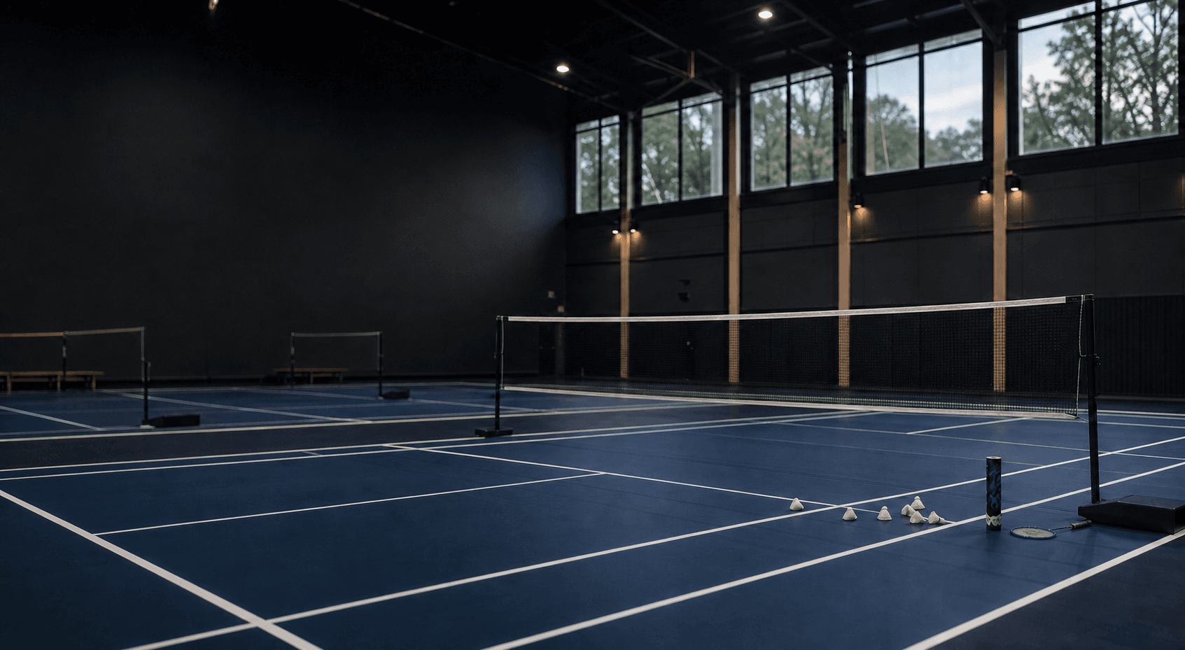 A prepared indoor badminton hall with courts and nets ready for a club session
